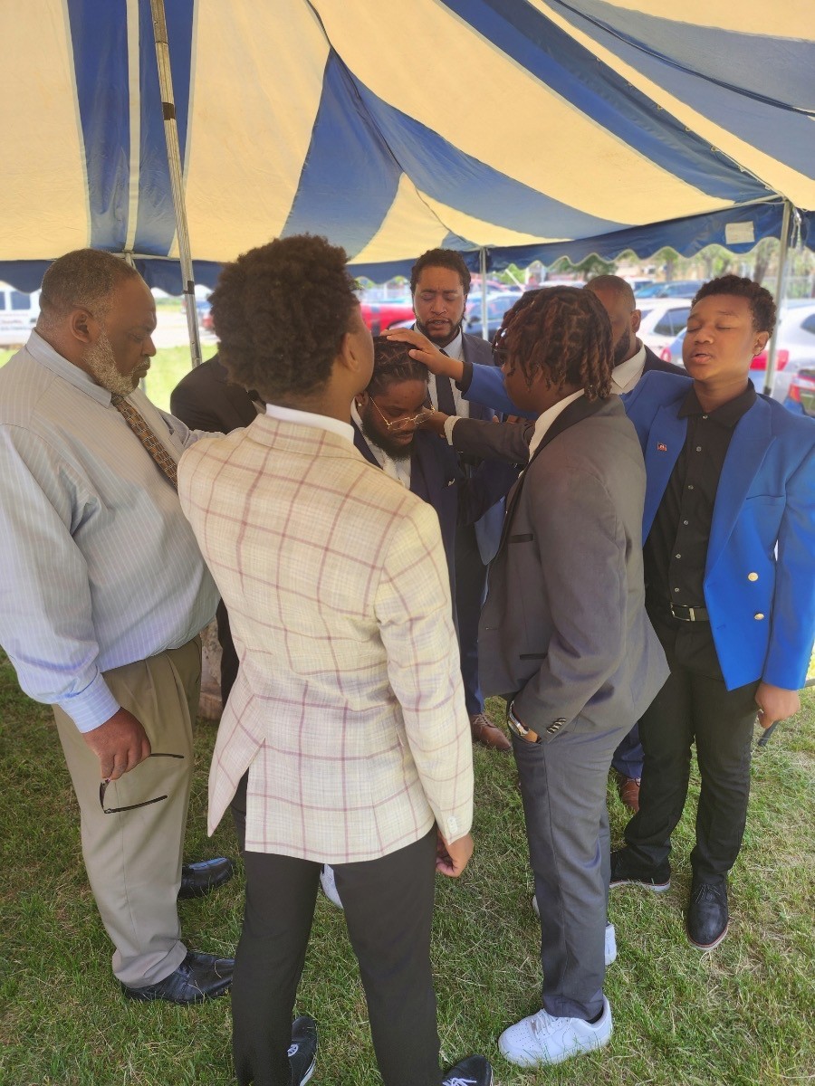 Brothers of New Jerusalem laying hands in prayer under the fellowship tent